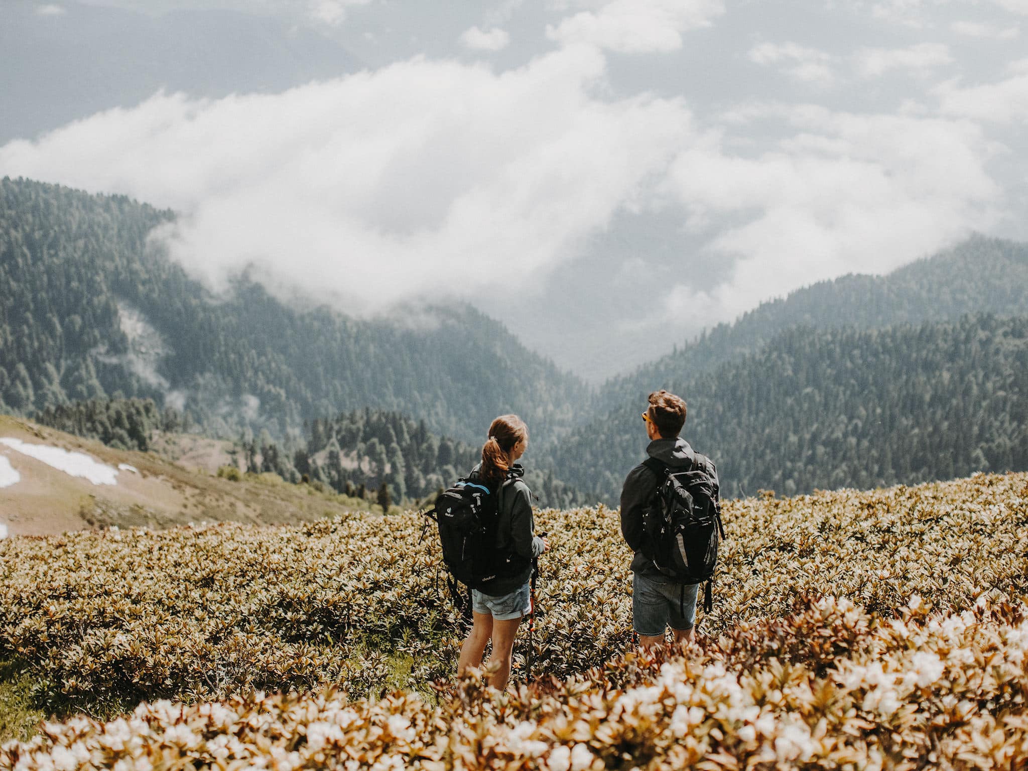 Zwei Wanderer in den Bergen genießen die Aussicht ins Tal