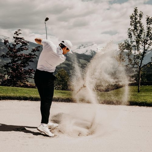 Golfer beim Abschlag im Sand